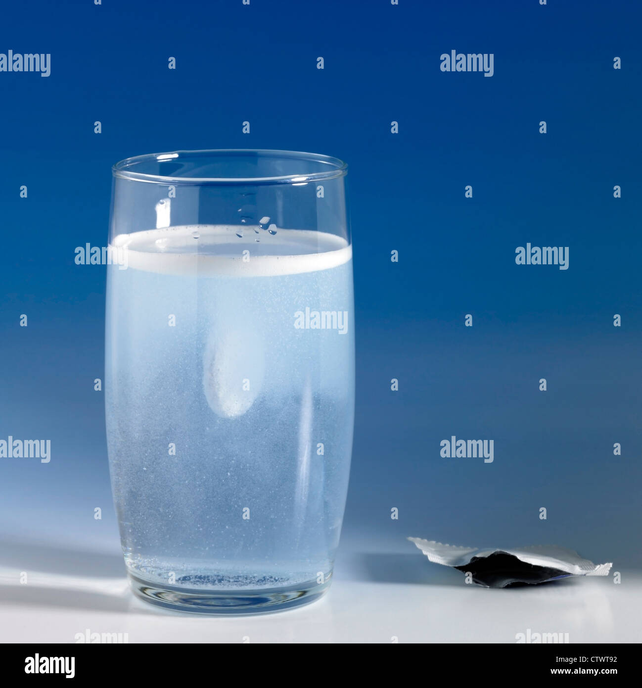 dissolving fizzy tablet in a glass of water. Studio photography in blue gradient back Stock Photo
