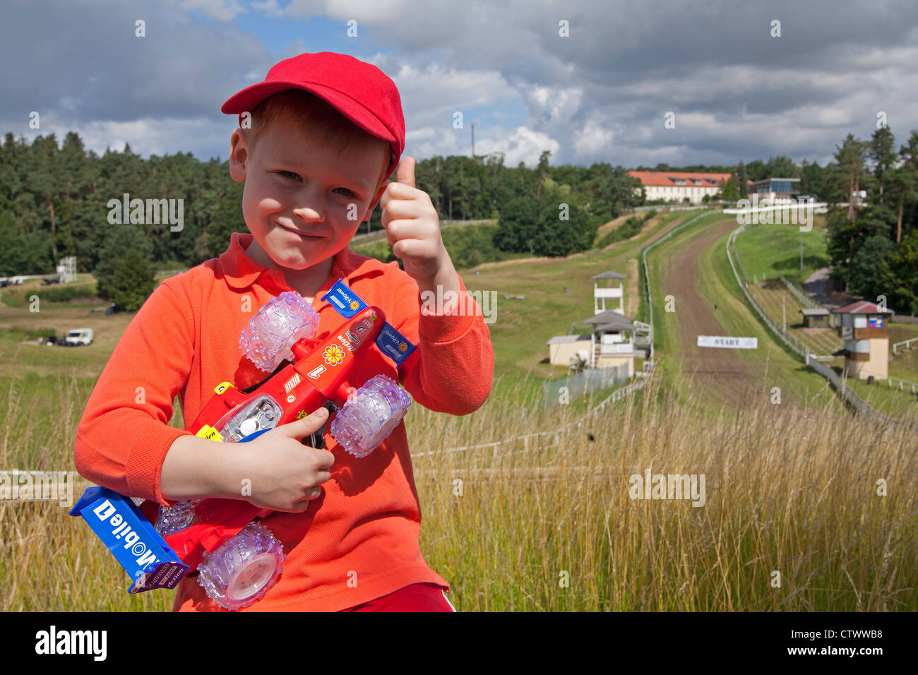 boy with toy racing car in front of racetrack, Teterow, Mecklenburg ...