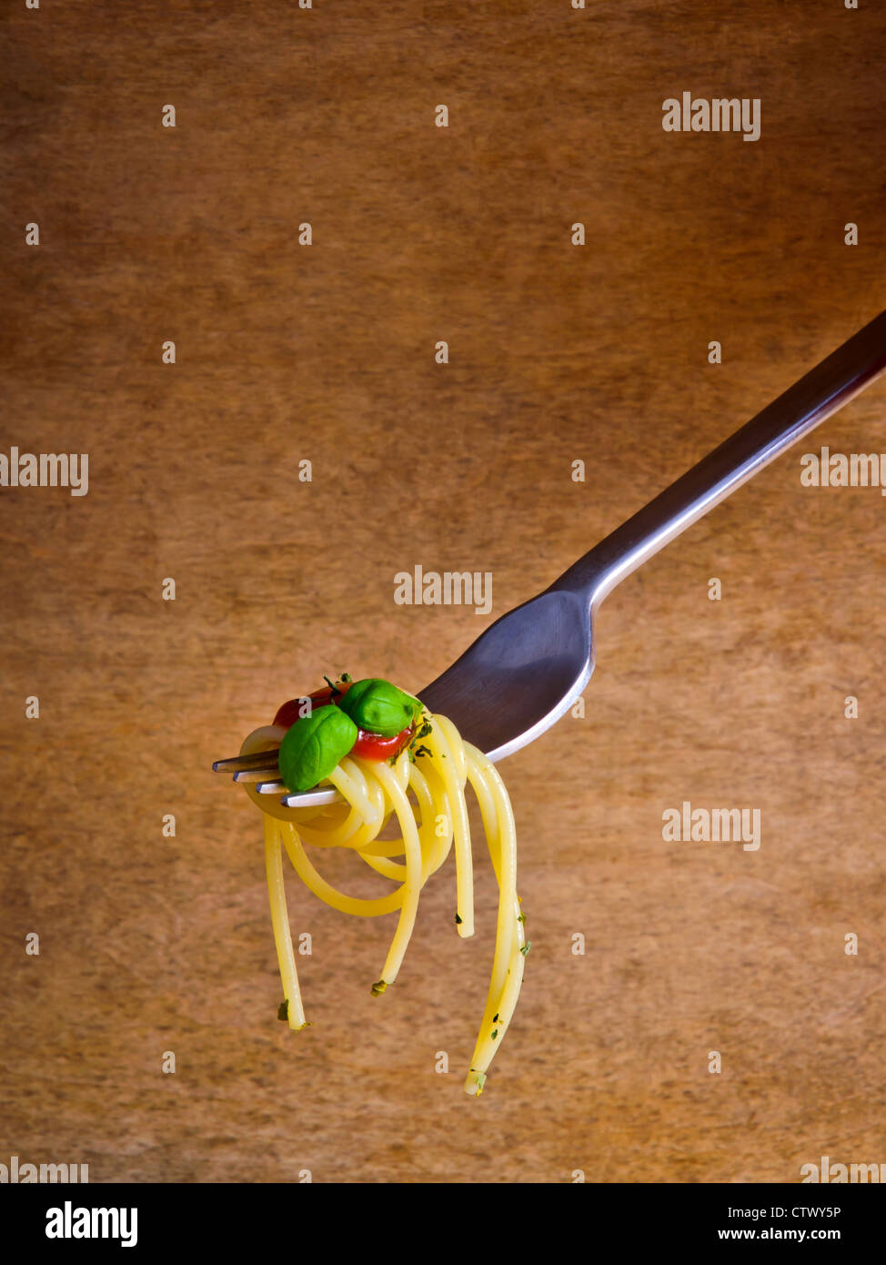 Italian spaghetti pasta on a fork against a vintage wooden background Stock Photo