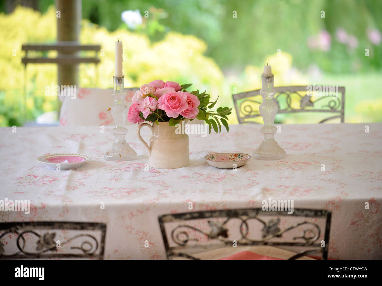 Glass candlesticks and pink roses on a table UK Stock Photo