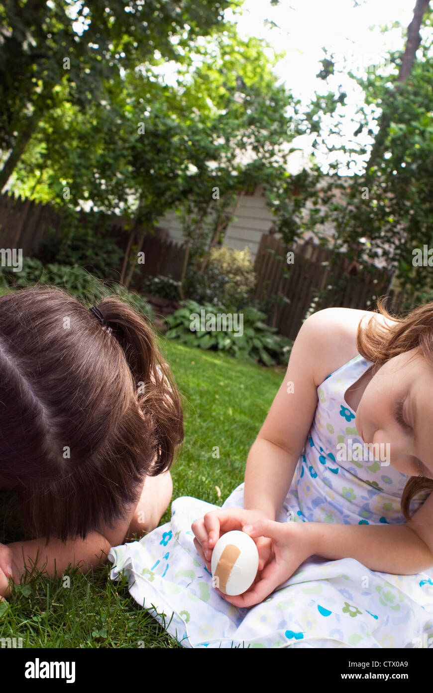 Two girls bandaging an egg with a bandaid. Stock Photo