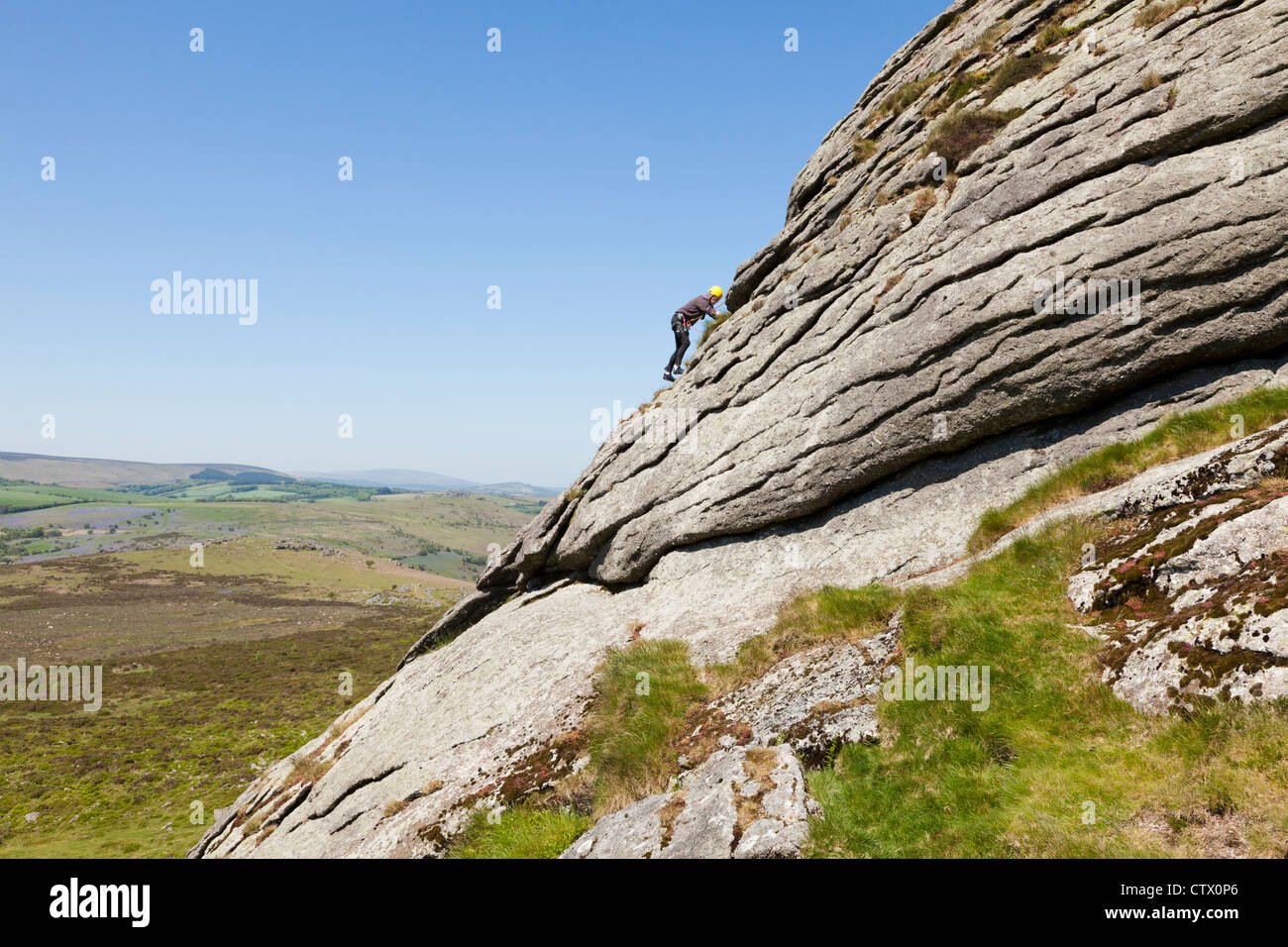 Man climbing on Haytor Rocks, a granite tor on Dartmoor, Devon, UK