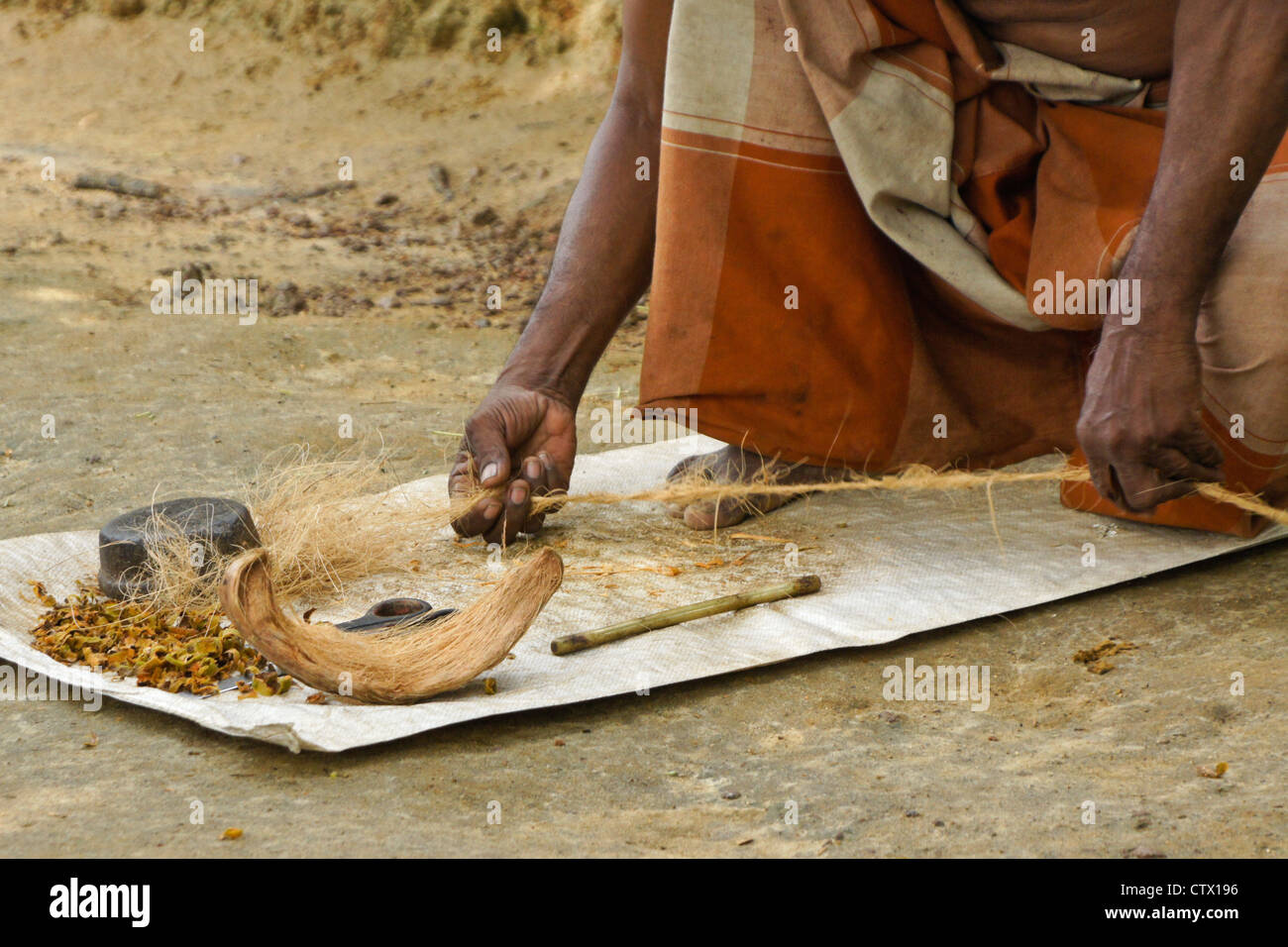 Man twisting coconut fiber (coir) into twine, Sri Lanka Stock Photo