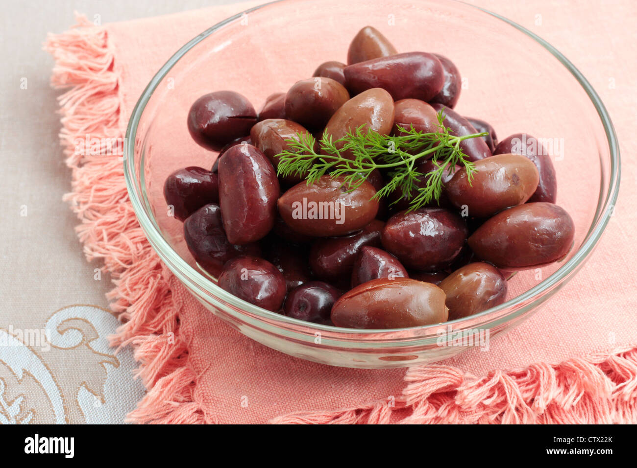 A dish of black Kalamata olives on a pink cloth background Stock Photo