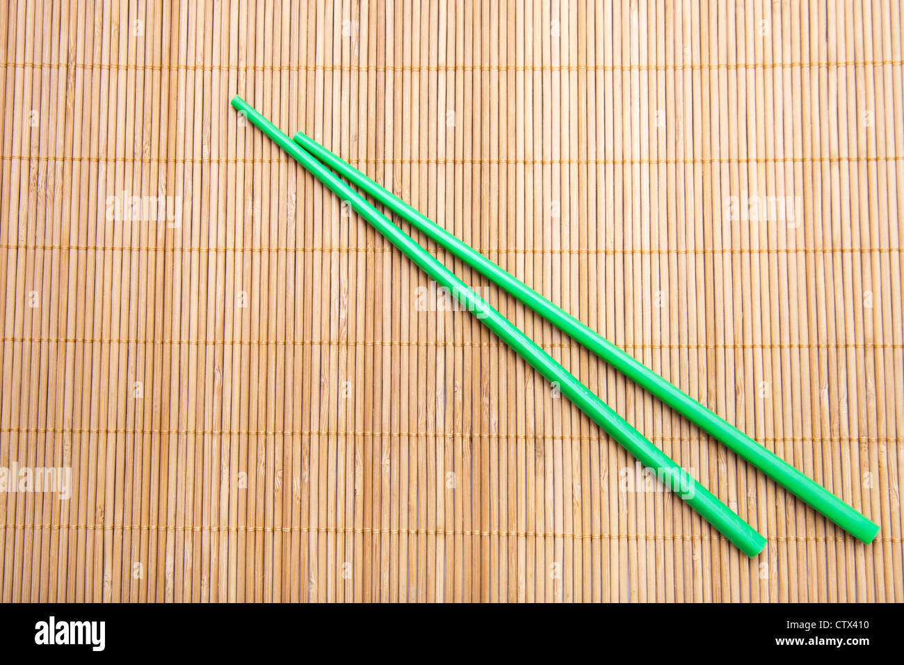 Green chopsticks on bamboo mat. Stock Photo