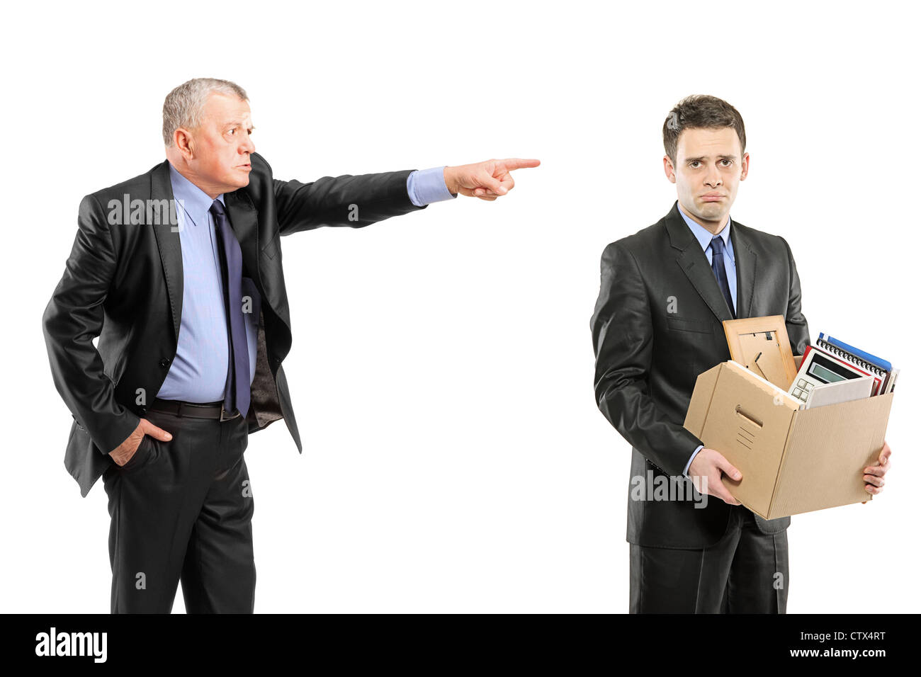 An angry boss firing a man carrying a box of personal items isolated on white background Stock Photo