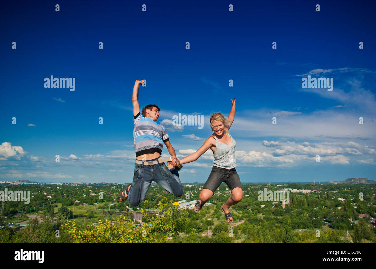 Boy and girl jumping against a background of beautiful sky Stock Photo ...