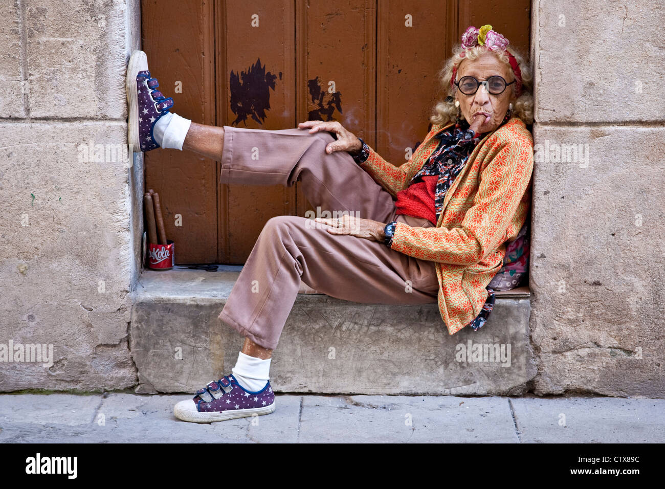 Old woman in a doorway smoking a Cigar, Havana, Cuba Stock Photo