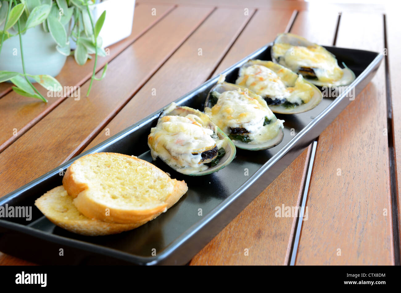 Side view of food call 'Baked mussel with cheese' served on the wooden table. Stock Photo