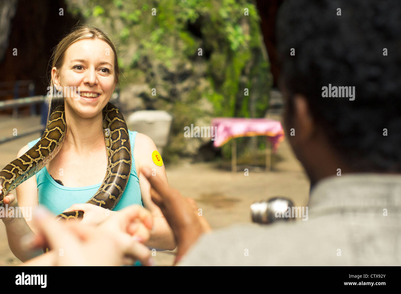 a caucasian woman tourist posed with snake in batu cave, kuala lumpur, malaysia. Stock Photo