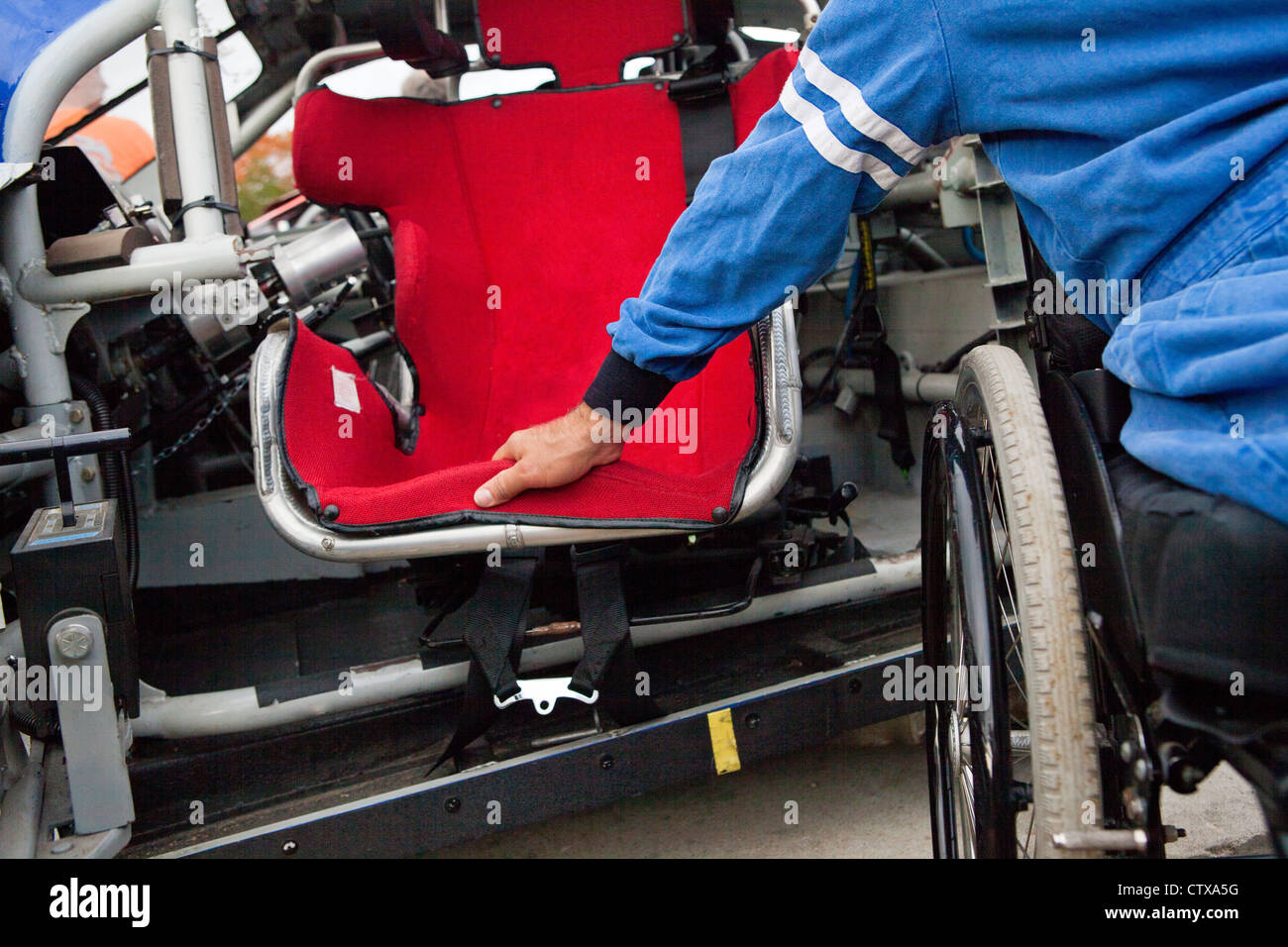Racer with spinal cord injury in wheelchair at swing away safety roll cage door of race car Stock Photo
