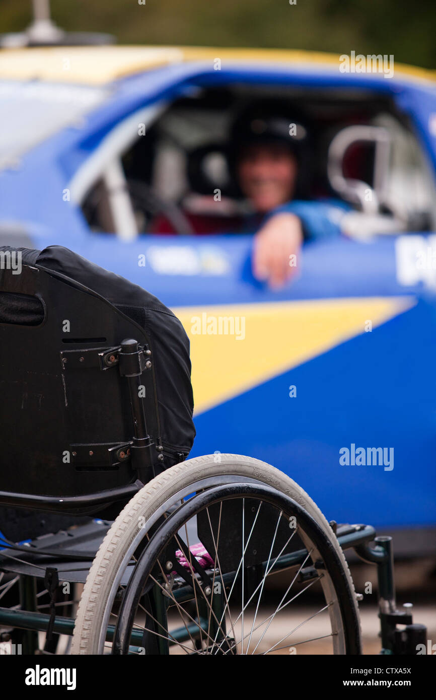 Wheelchair in front of stock car modified for disability racing Stock