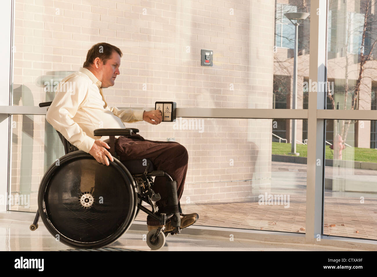 Businessman with spinal cord injury in wheelchair using automatic door