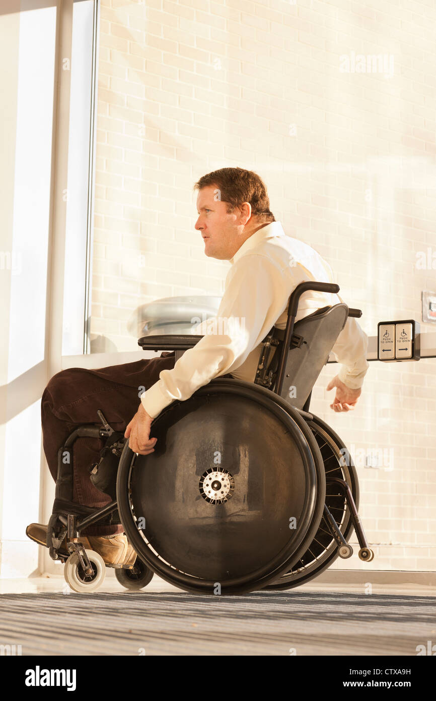 Businessman with spinal cord injury in wheelchair using automatic door