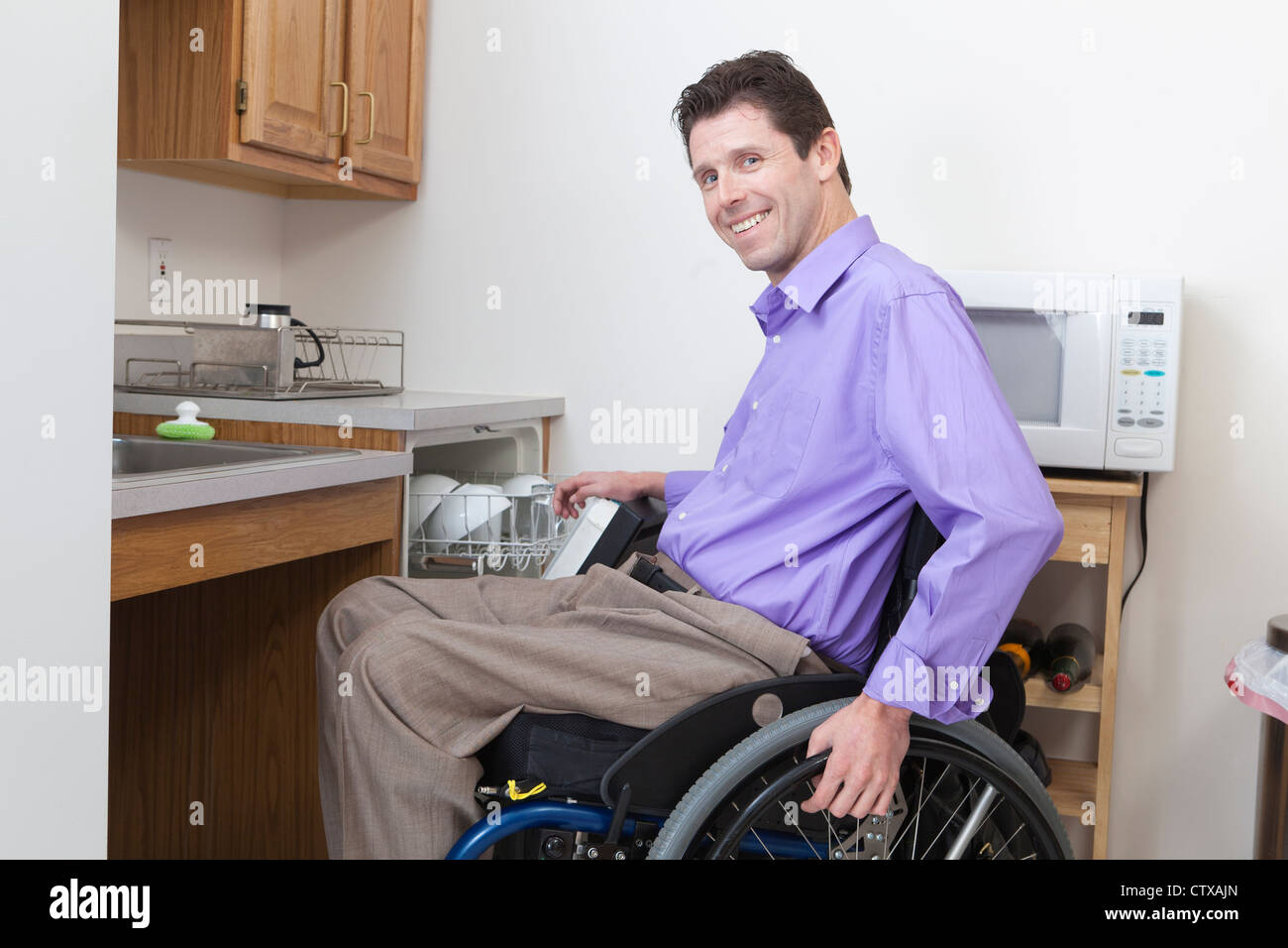 Man in wheelchair with spinal cord injury putting dishes in an