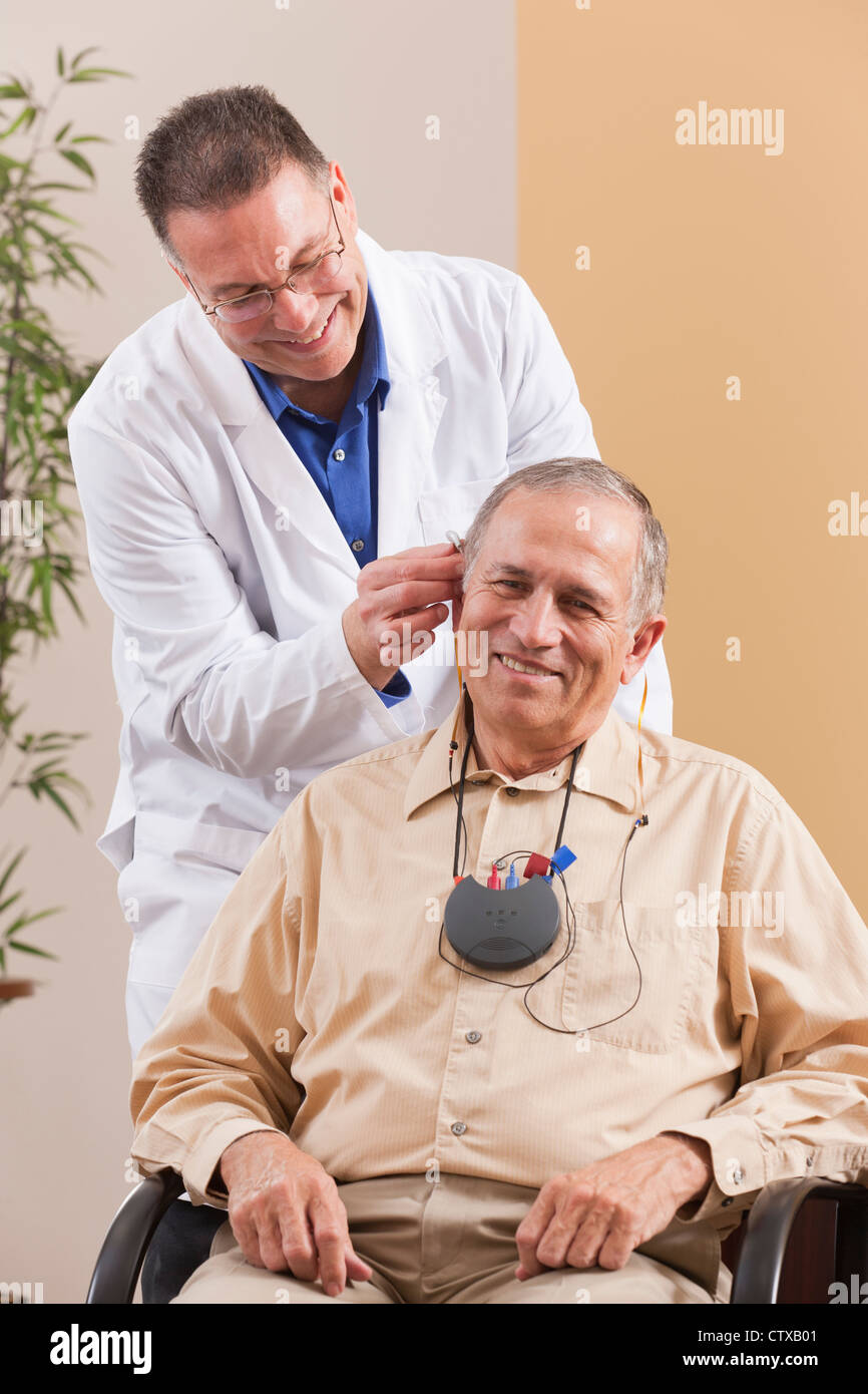 Audiologist adjusting behindtheear hearing aid in a patient's ear