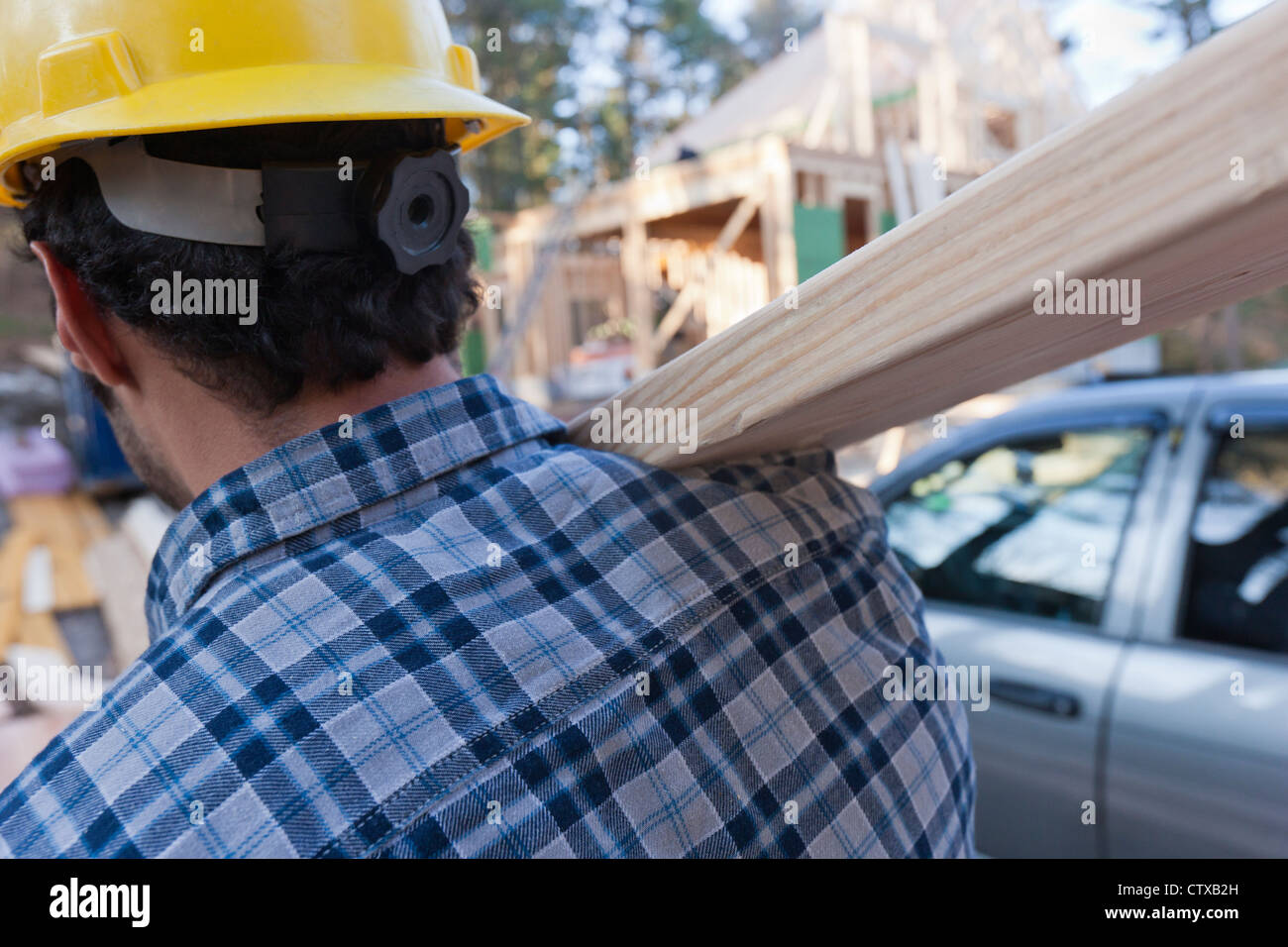 Carpenter carrying a rafter for house under construction Stock Photo