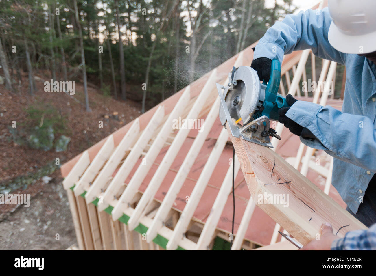 Carpenter using a circular saw to recut rafter bevel Stock Photo