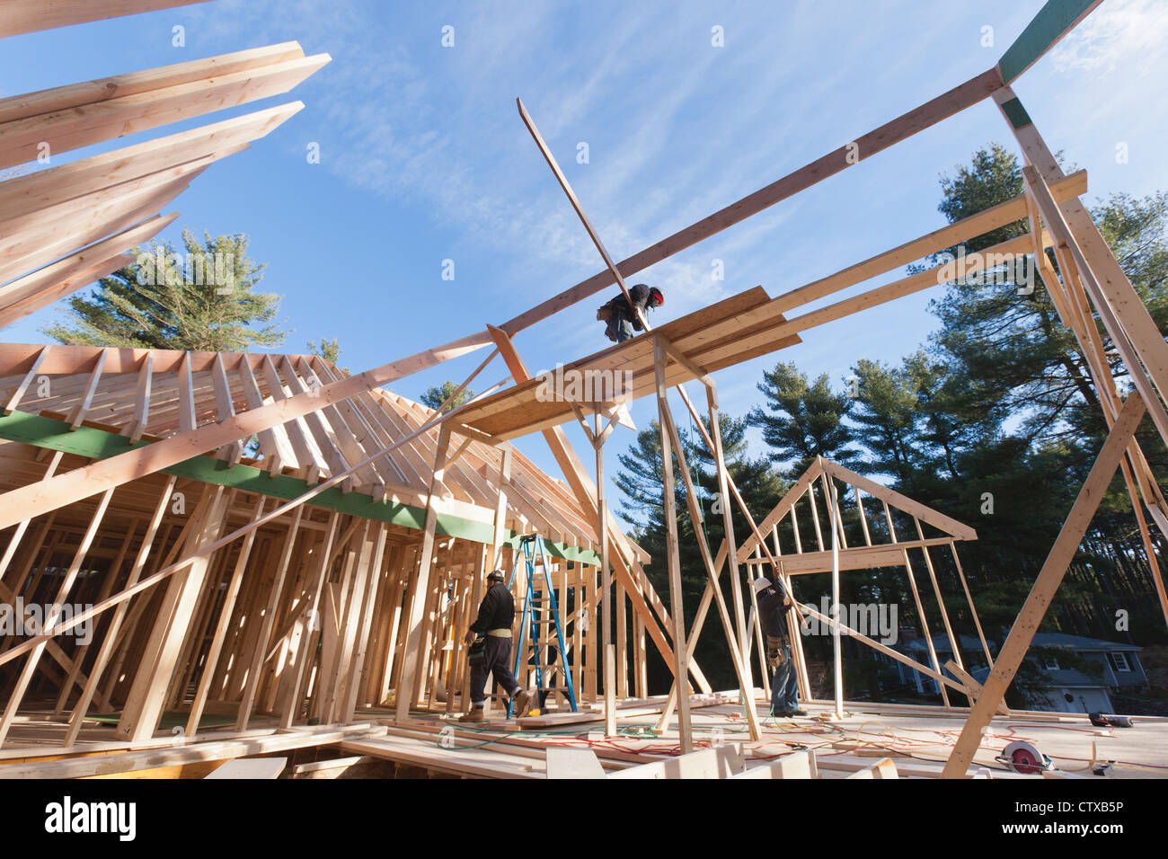Carpenter lifting rafter into place on upper roof Stock Photo - Alamy
