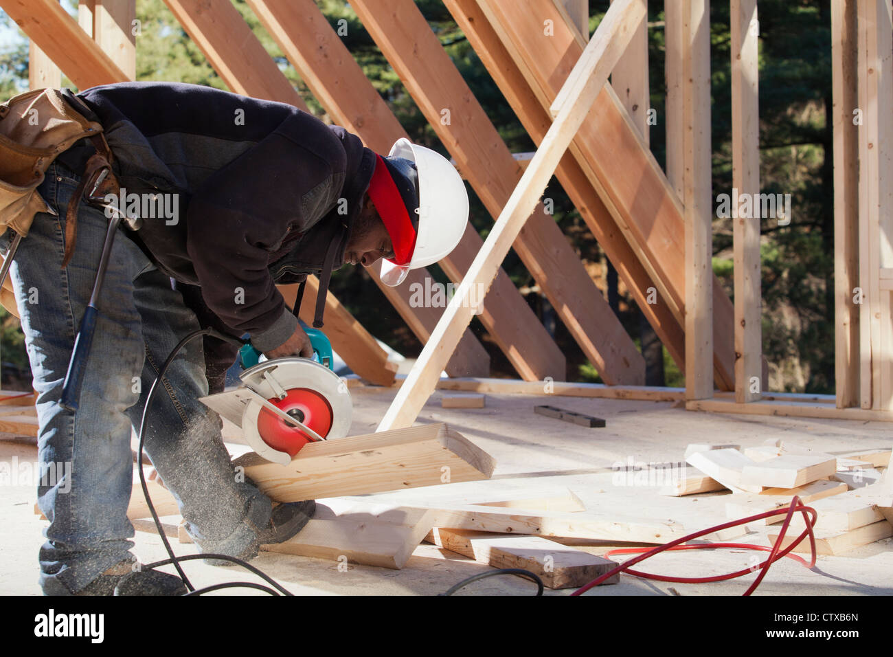 Carpenter cutting bevel on rafter with a circular saw Stock Photo