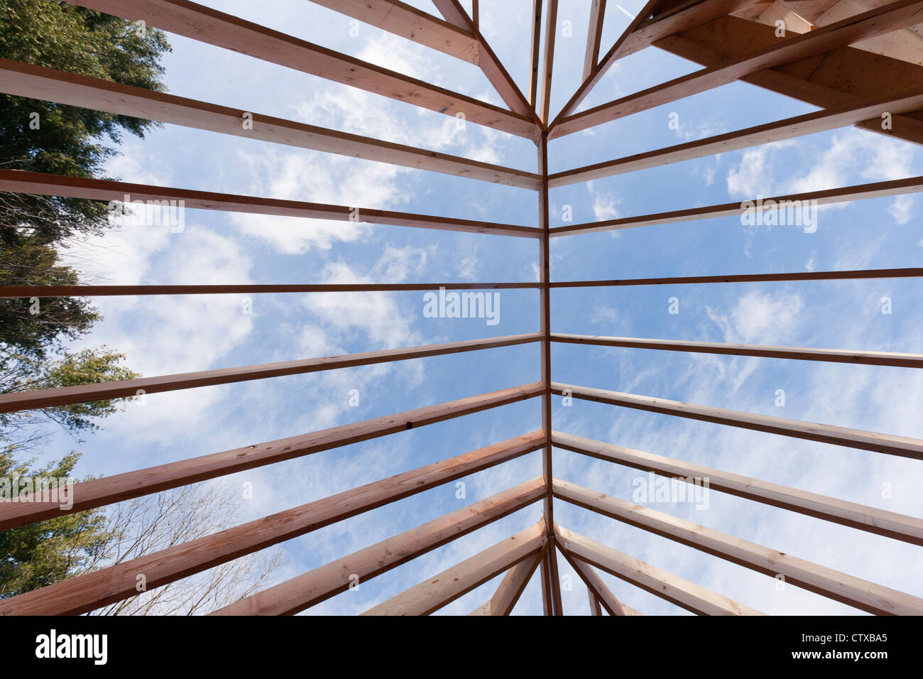 Low angle view of hip roof rafters viewed toward sky Stock Photo