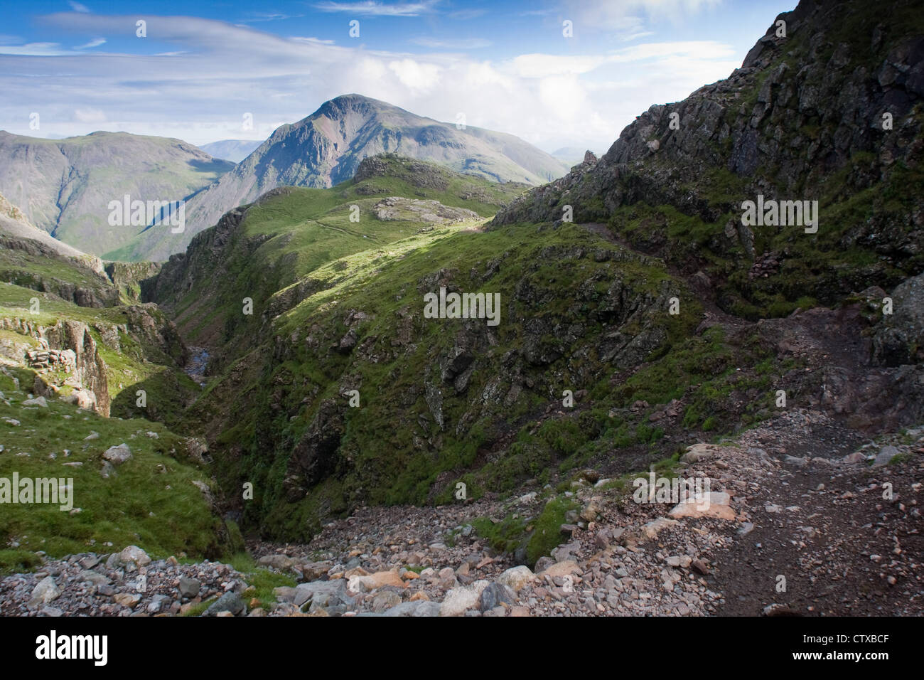 The Corridor Route path, right, which leads to Scafell Pike and Piers Gill, with Great Gable in the distance Stock Photo