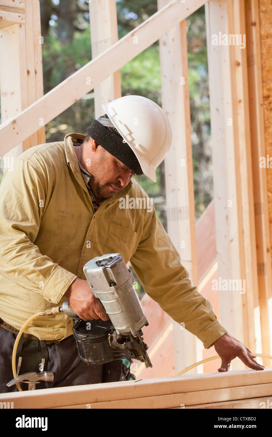 Carpenter using a nail gun on studs Stock Photo Alamy