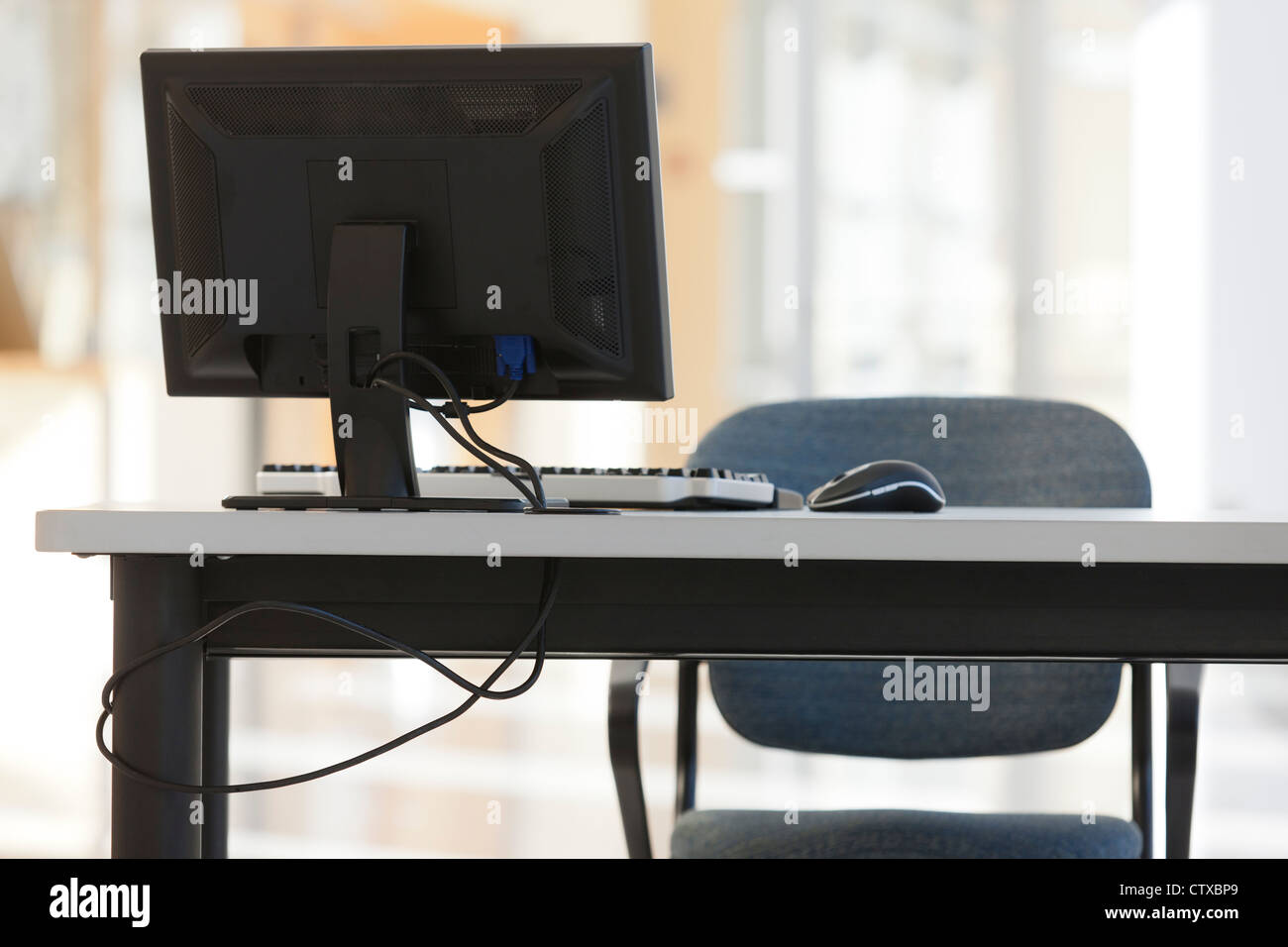 Computer equipment on desk with chair Stock Photo