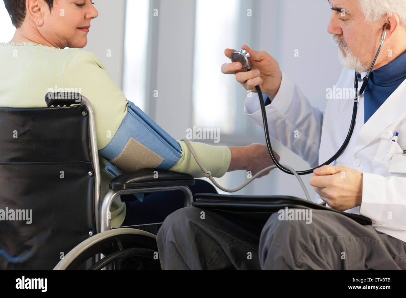 Doctor with muscular dystrophy in wheelchair checking the blood