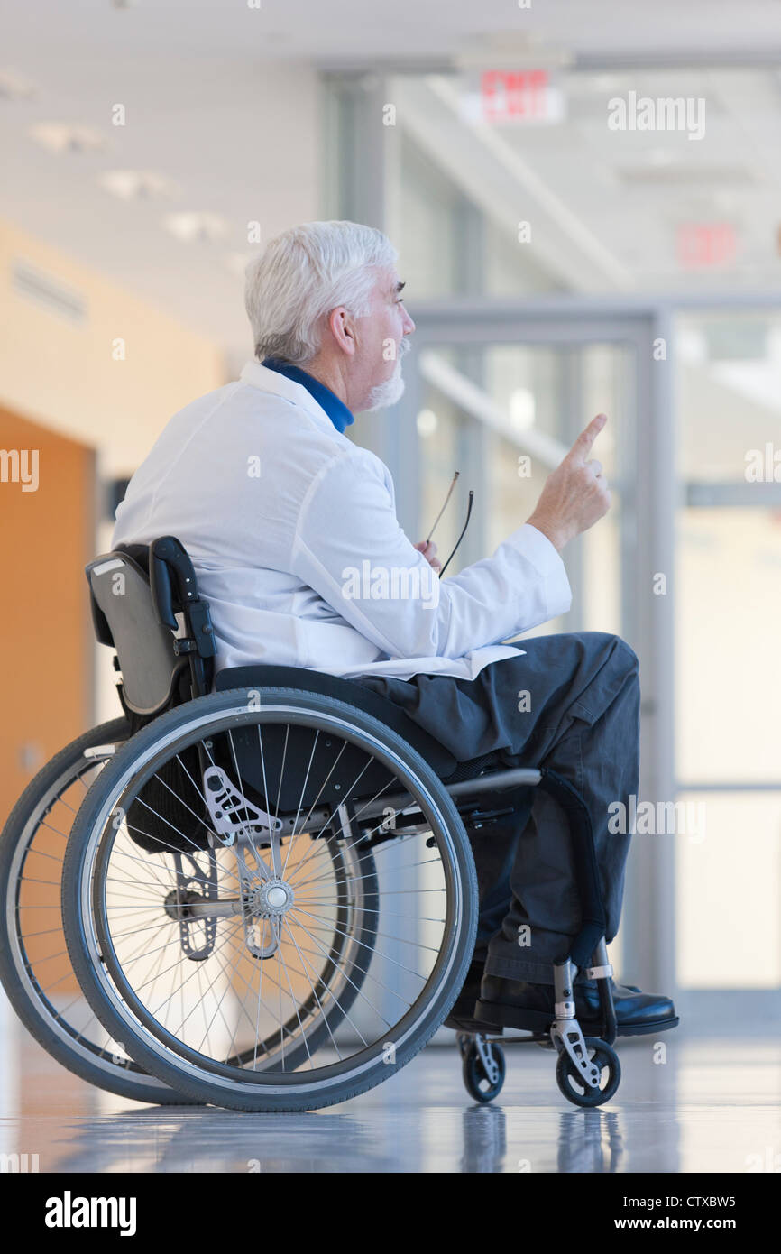 Doctor with muscular dystrophy in wheelchair in hospital hallway Stock