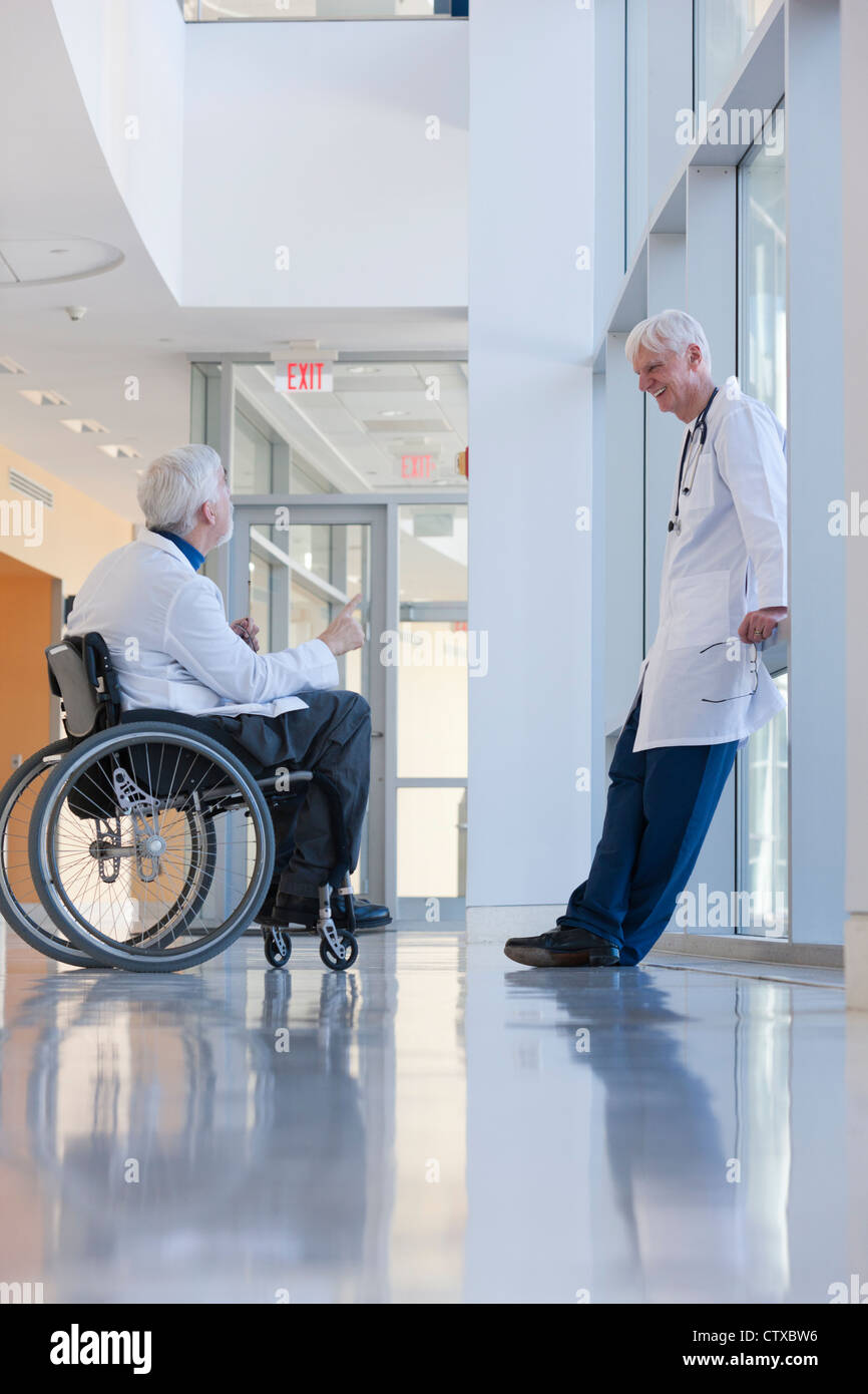 Doctor with muscular dystrophy in wheelchair talking with another