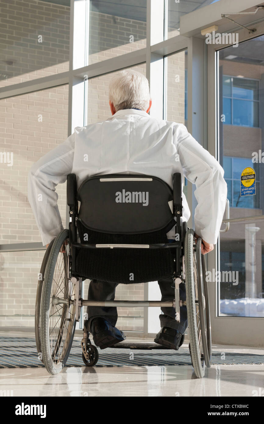 Doctor with muscular dystrophy in wheelchair at hospital entrance Stock