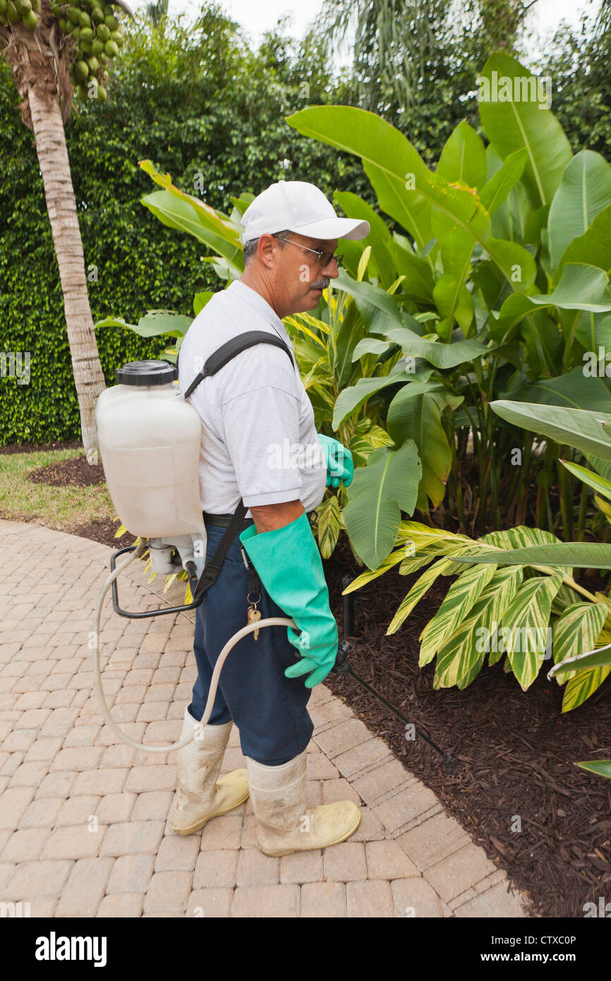 Pest control technician with portable spray rig using spray nozzle and