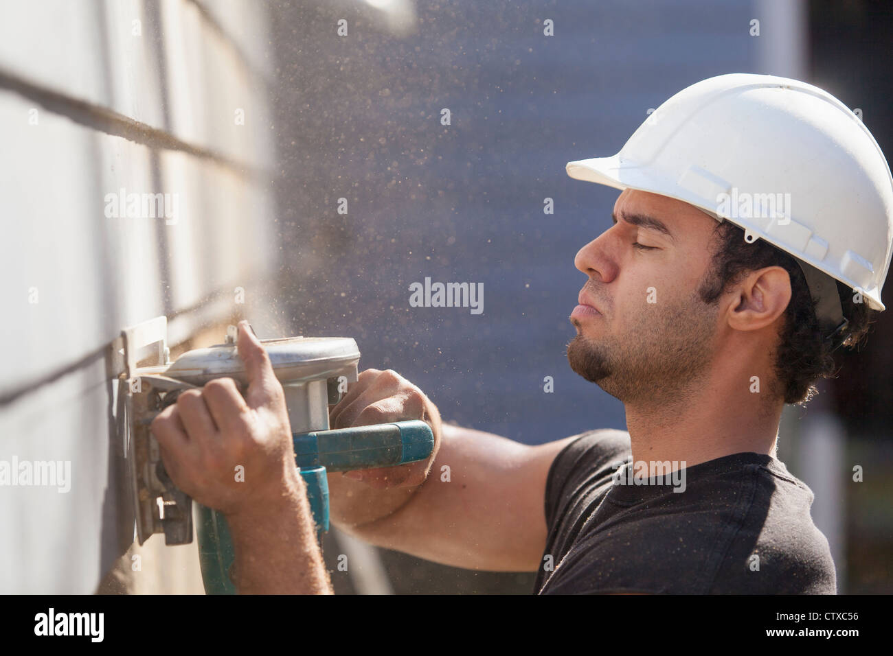 Hispanic carpenter trimming house siding for installation of new deck