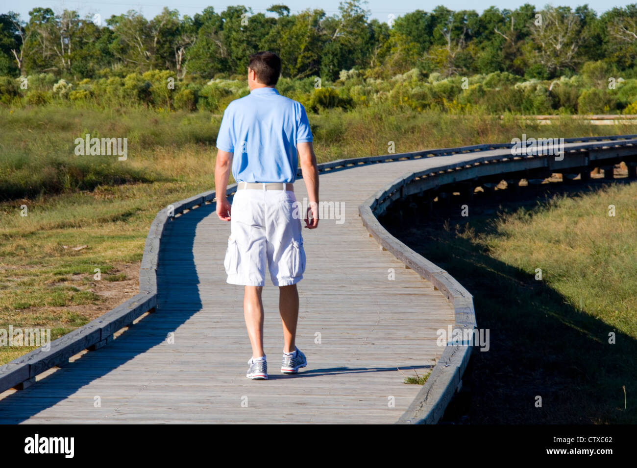 Visitors hike a boardwalk through marshland near the Cameron Prairie National Wildlife Refuge Visitor Center, LA, USA Stock Photo