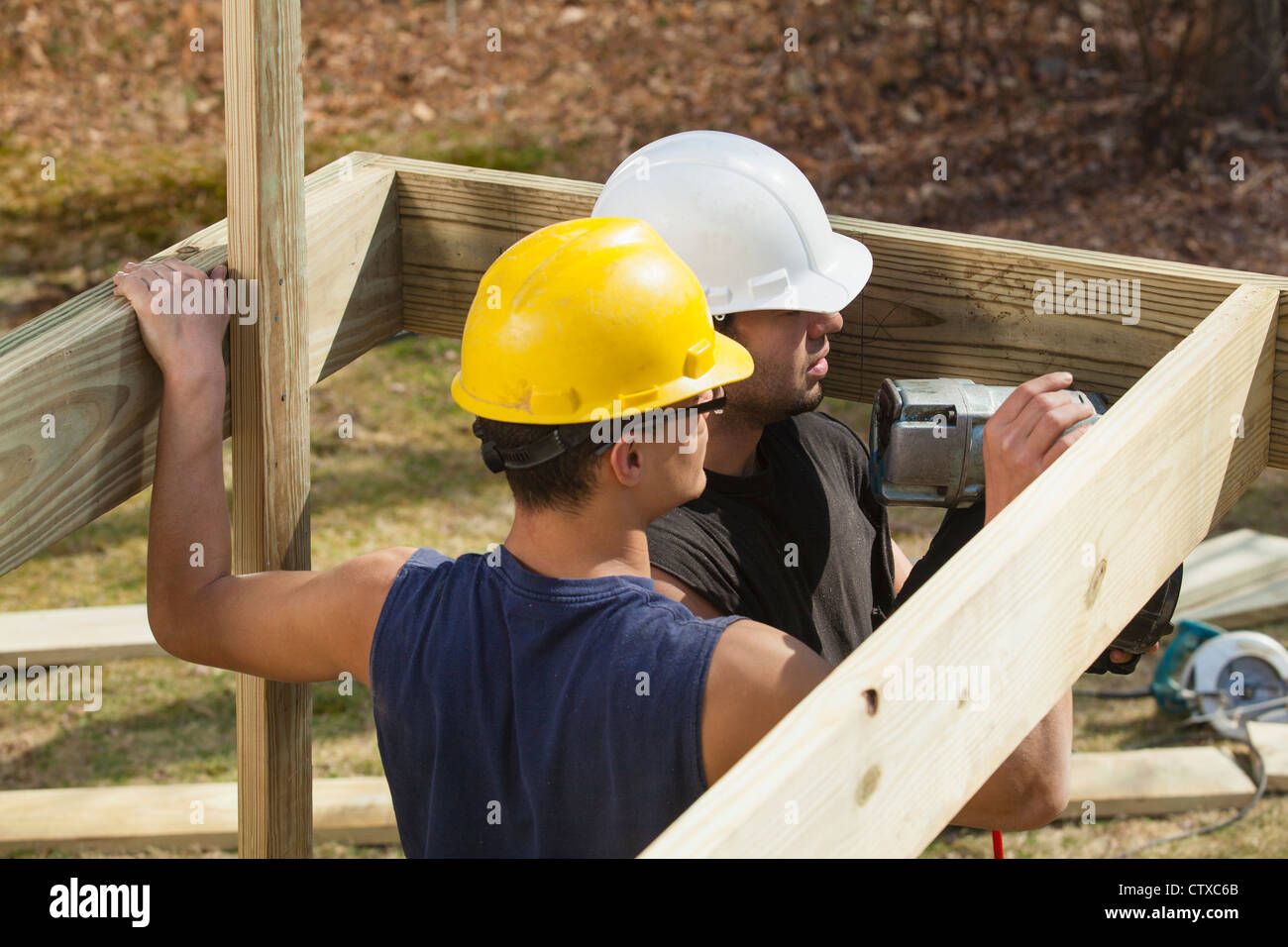 Hispanic carpenters using nail gun on pressure treated deck joists