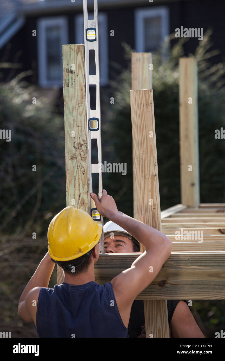 Hispanic carpenters using a level on deck post construction Stock Photo ...