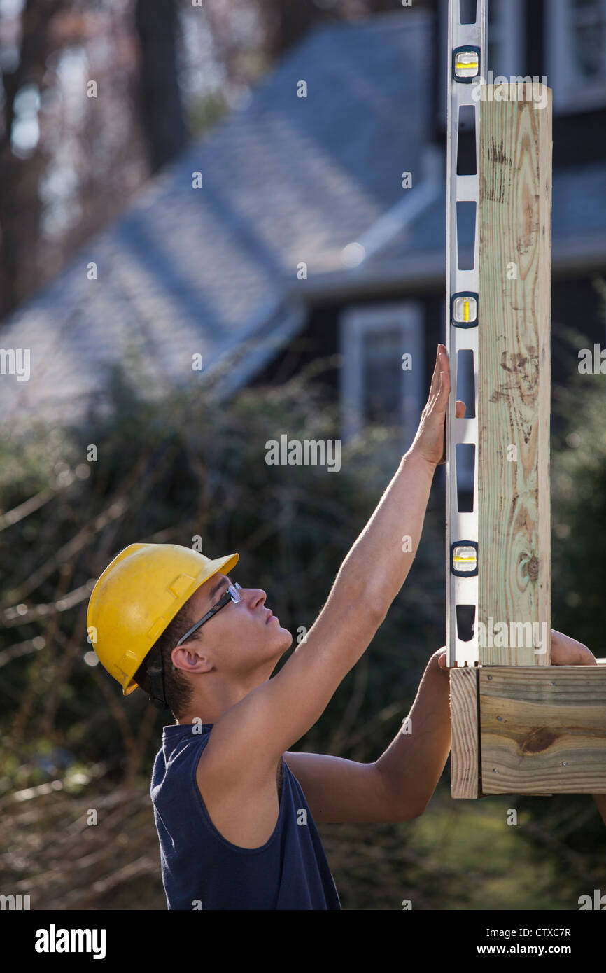 Hispanic carpenter using a level on deck post construction Stock Photo ...