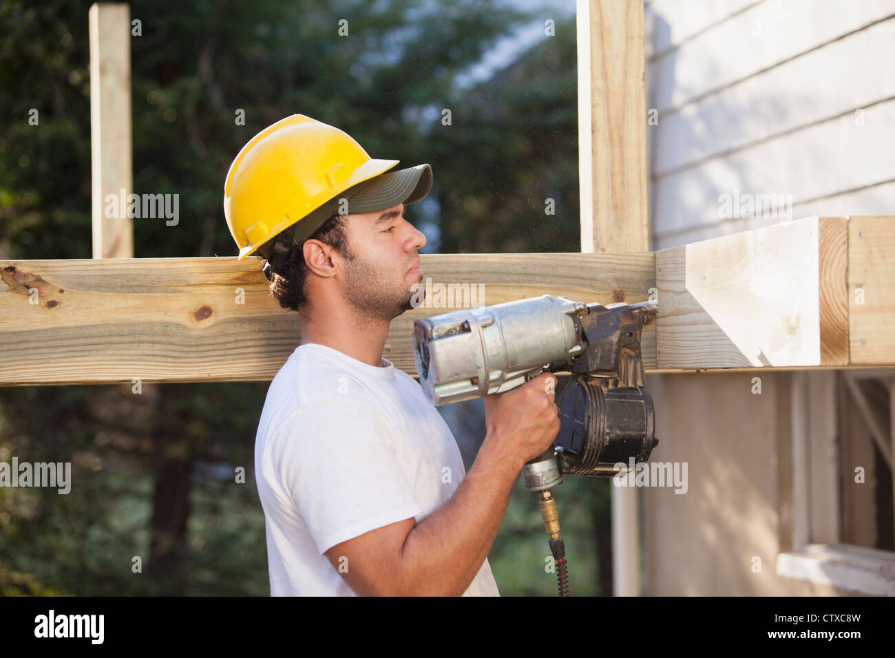 Hispanic carpenter using nail gun on home deck construction Stock Photo