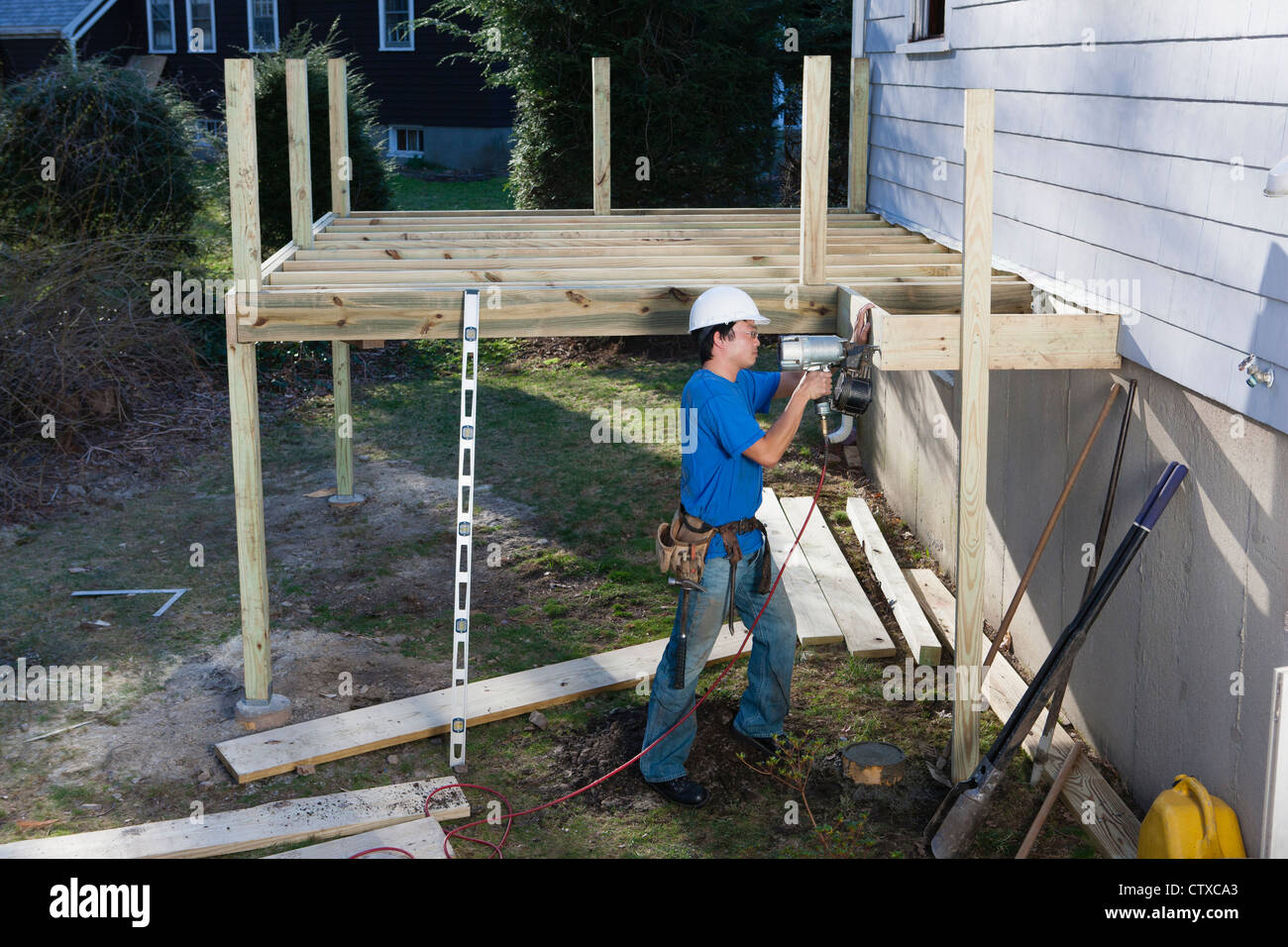 Carpenter using nail gun to install deck joists on home Stock Photo