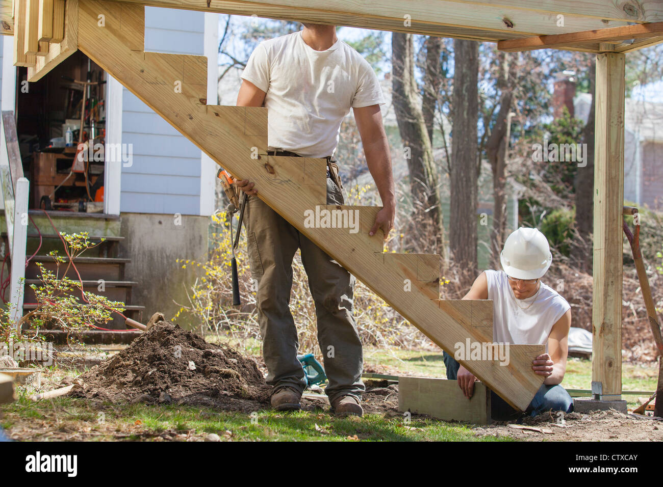 Hispanic carpenters installing stair stringer on house deck