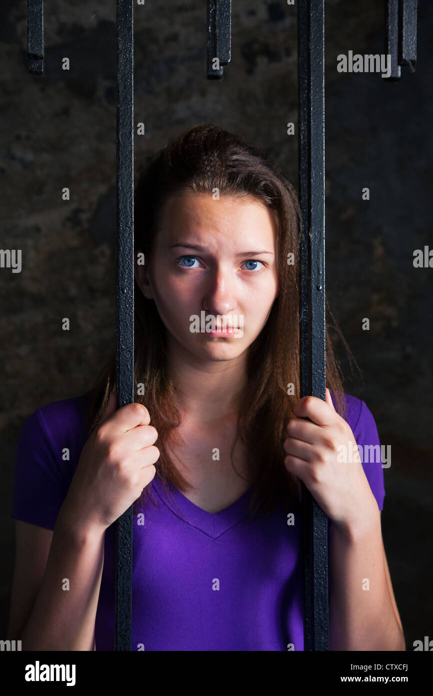 Young woman looking from behind the bars Stock Photo