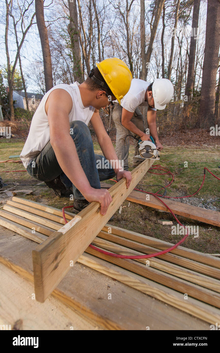 Hispanic carpenter using circular saw on pressure treated decking Stock Photo