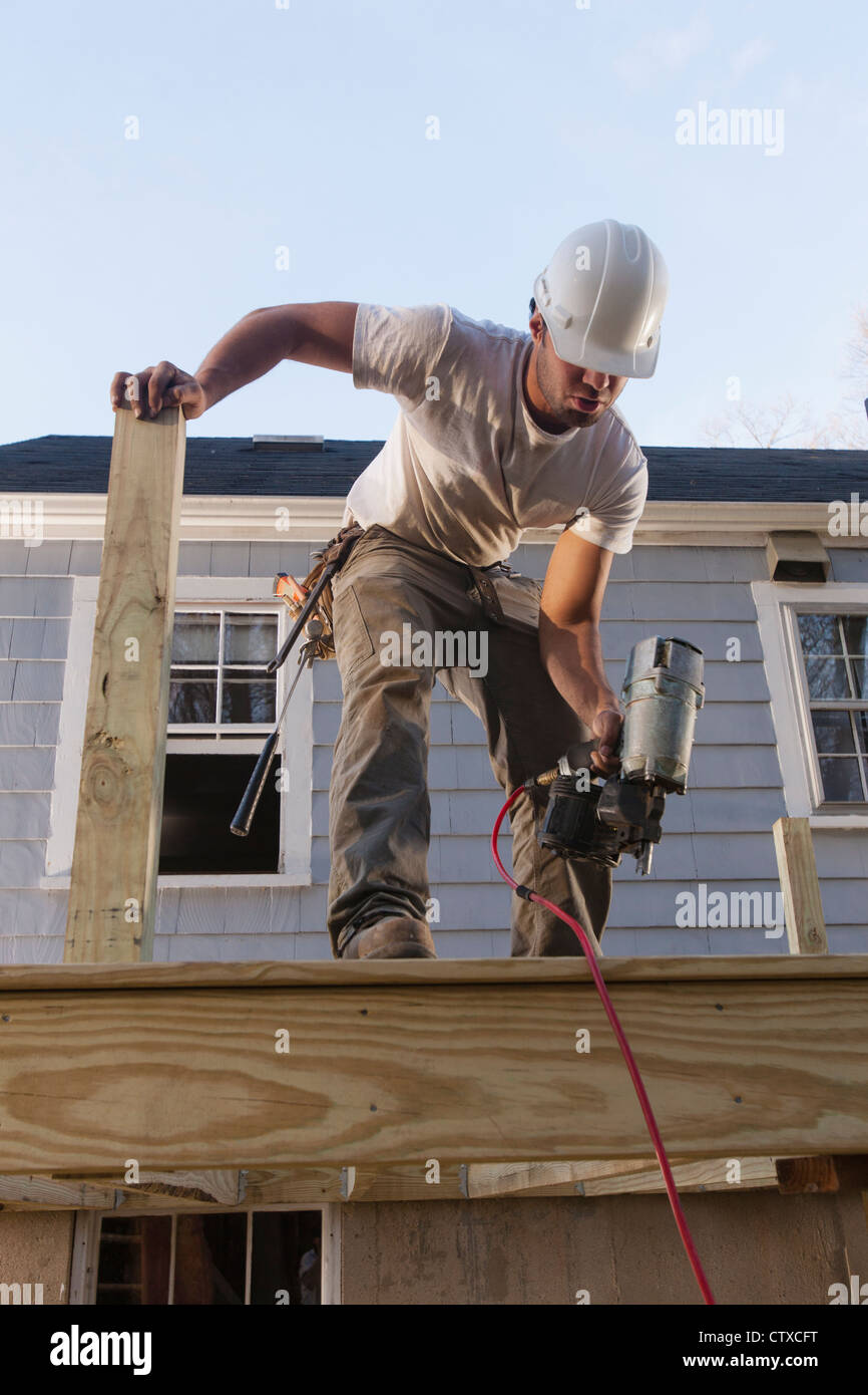 Hispanic carpenter using nail gun on home deck construction Stock Photo