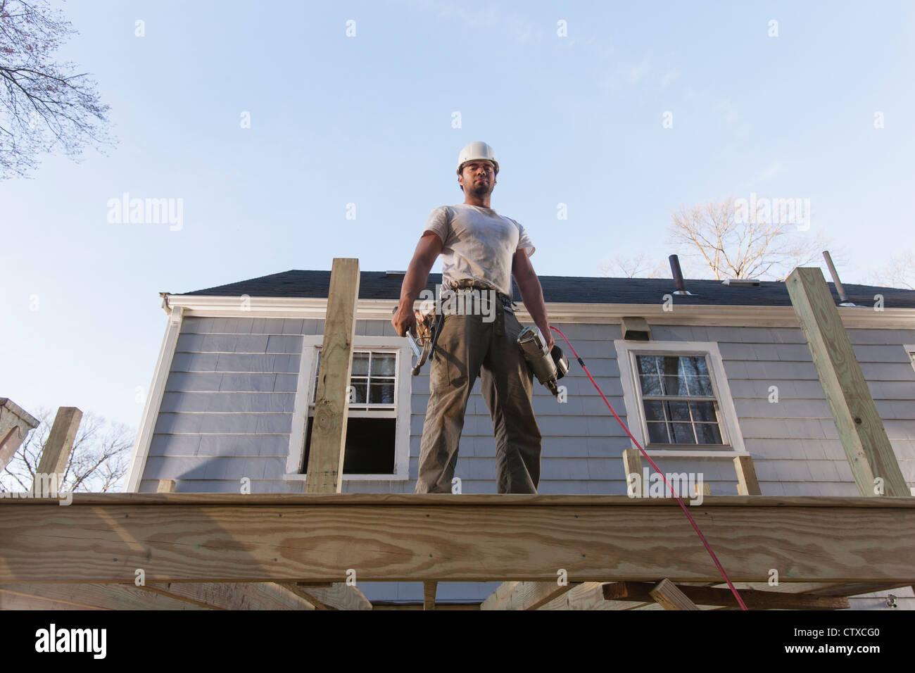 Hispanic carpenter using nail gun on home deck construction Stock Photo