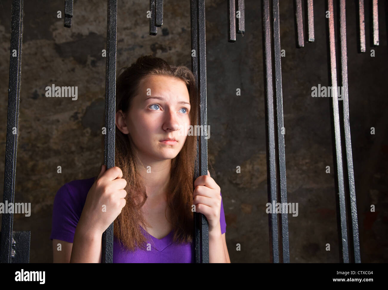 Young woman looking from behind the bars Stock Photo