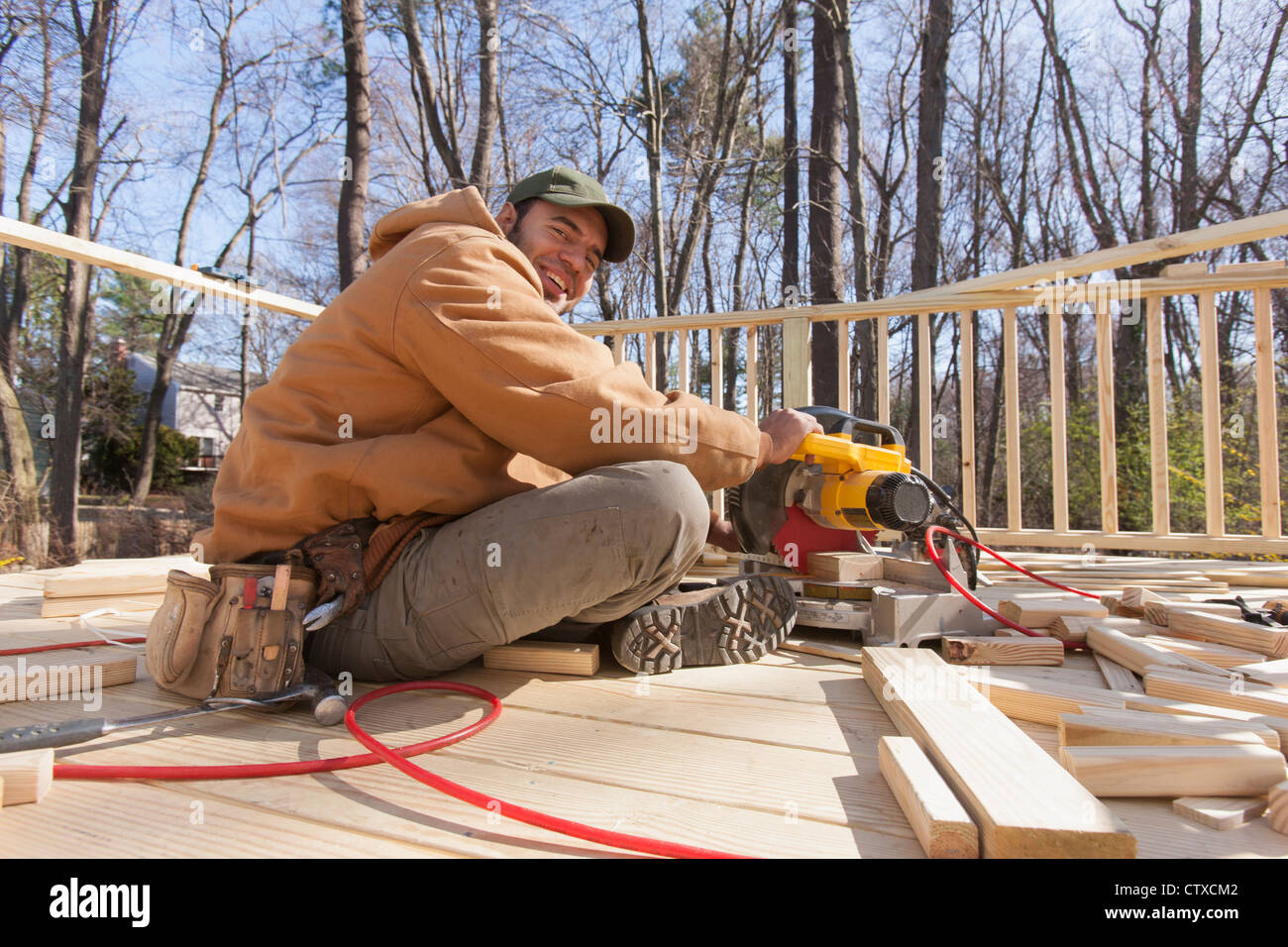 Hispanic carpenter using chop saw to cut deck railing cap Stock Photo