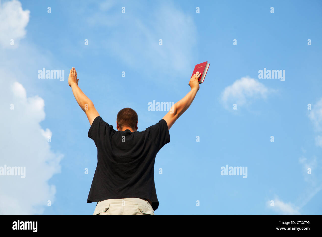 Young man staying with raised hands against blue sky Stock Photo - Alamy