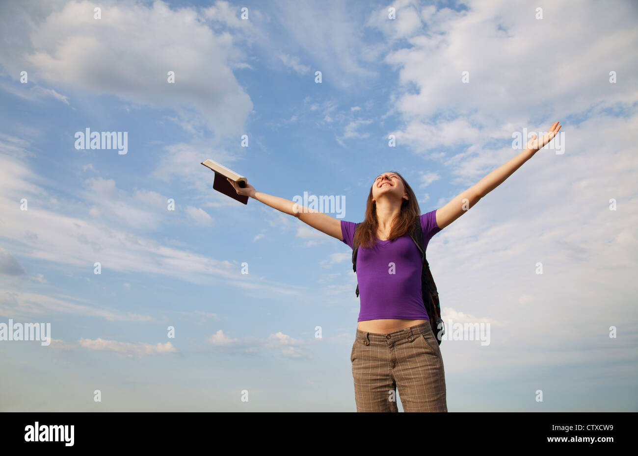 Young woman staying with raised hands against blue sky Stock Photo - Alamy