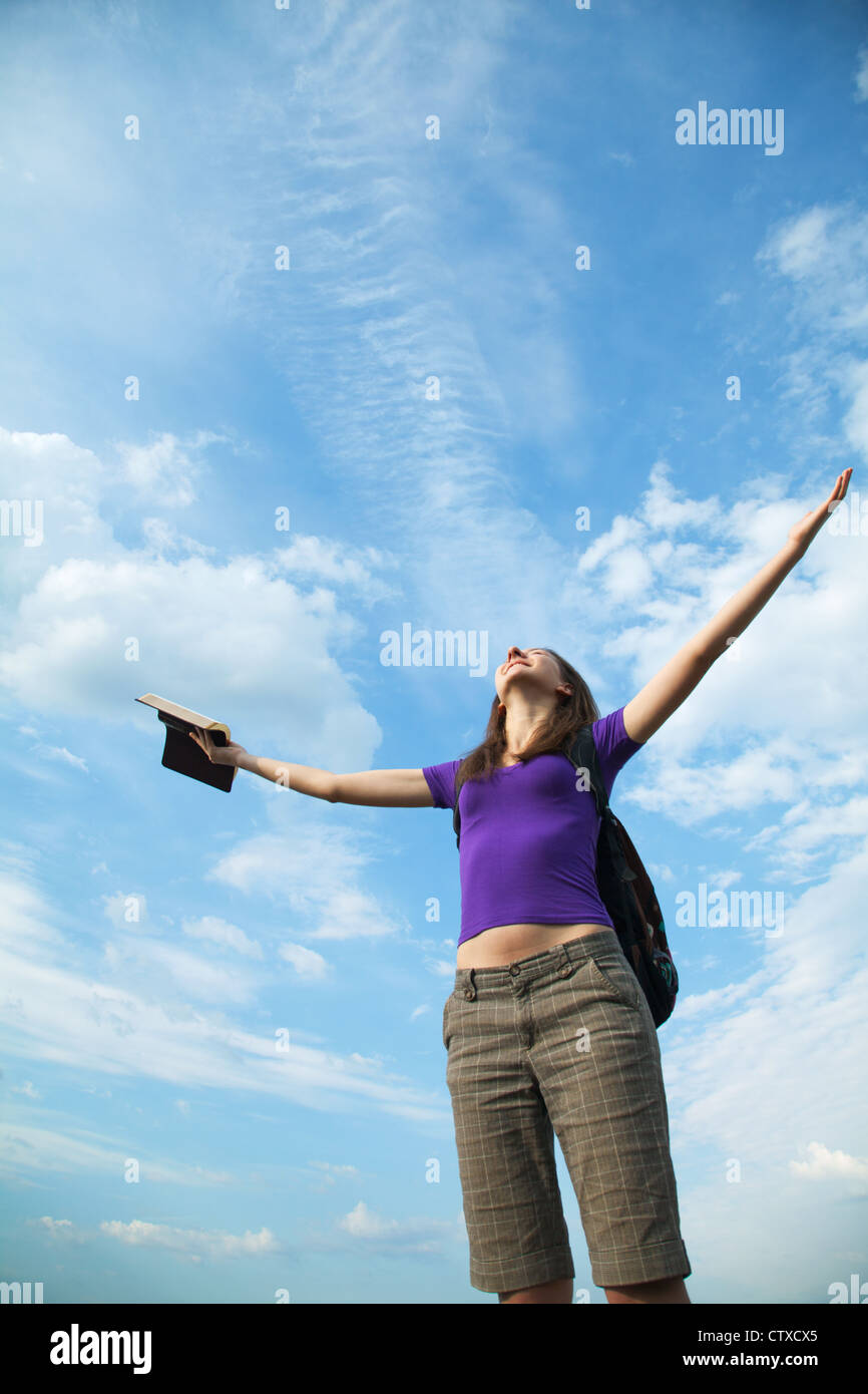 Young woman staying with raised hands against blue sky Stock Photo - Alamy